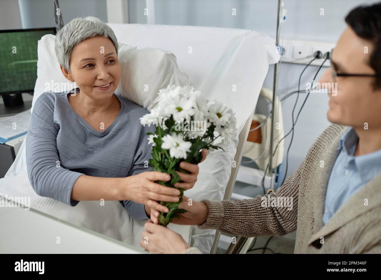 Senior sick woman getting flowers from her son while he visiting her in