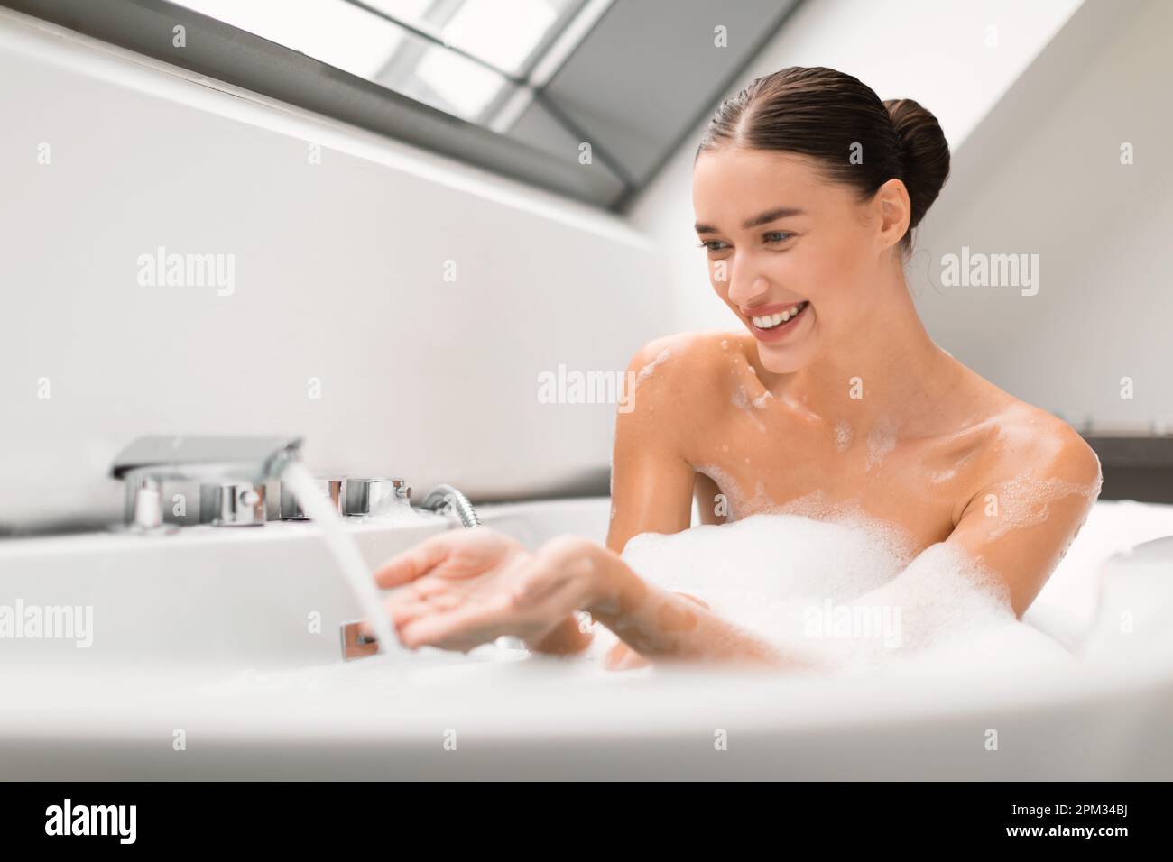 Cheerful Lady Taking Bath Putting Hands Under Running Water Indoor