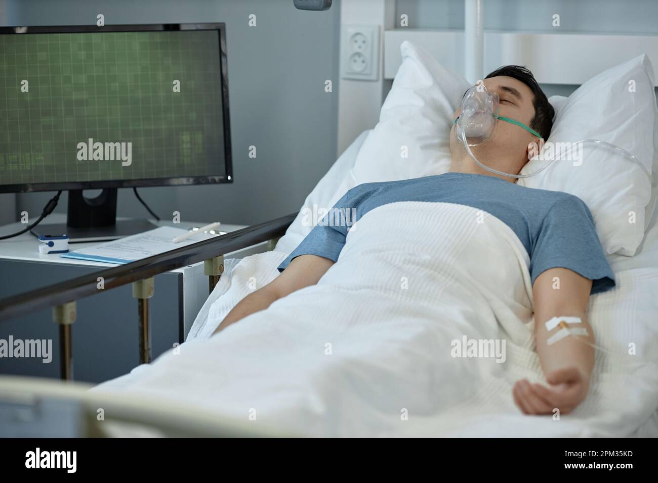 Young man lying on bed with oxygen mask on his face during treatment in