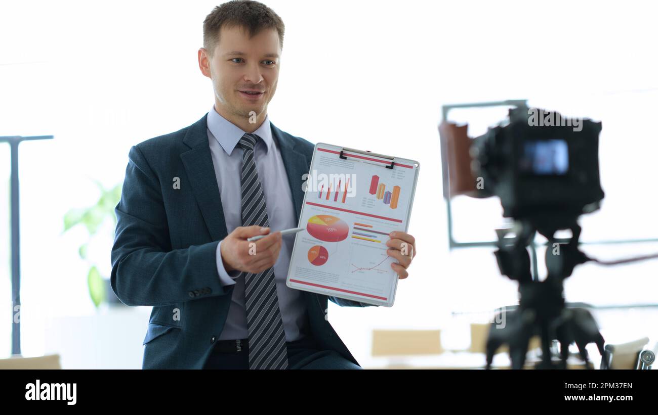 Business coach blogger showing graphs on documents in front of camera in office Stock Photo