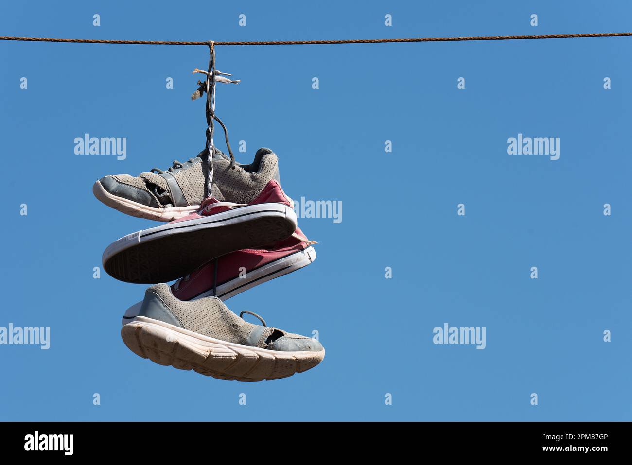 Shoe throwing tradition old shoes hanging on wires. Sneakers hanging on