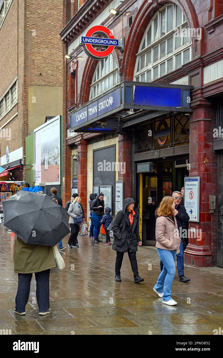 Camden Town, London: Outside Camden Town tube station on Camden High Street. People standing by the underground station in the rain. Stock Photo