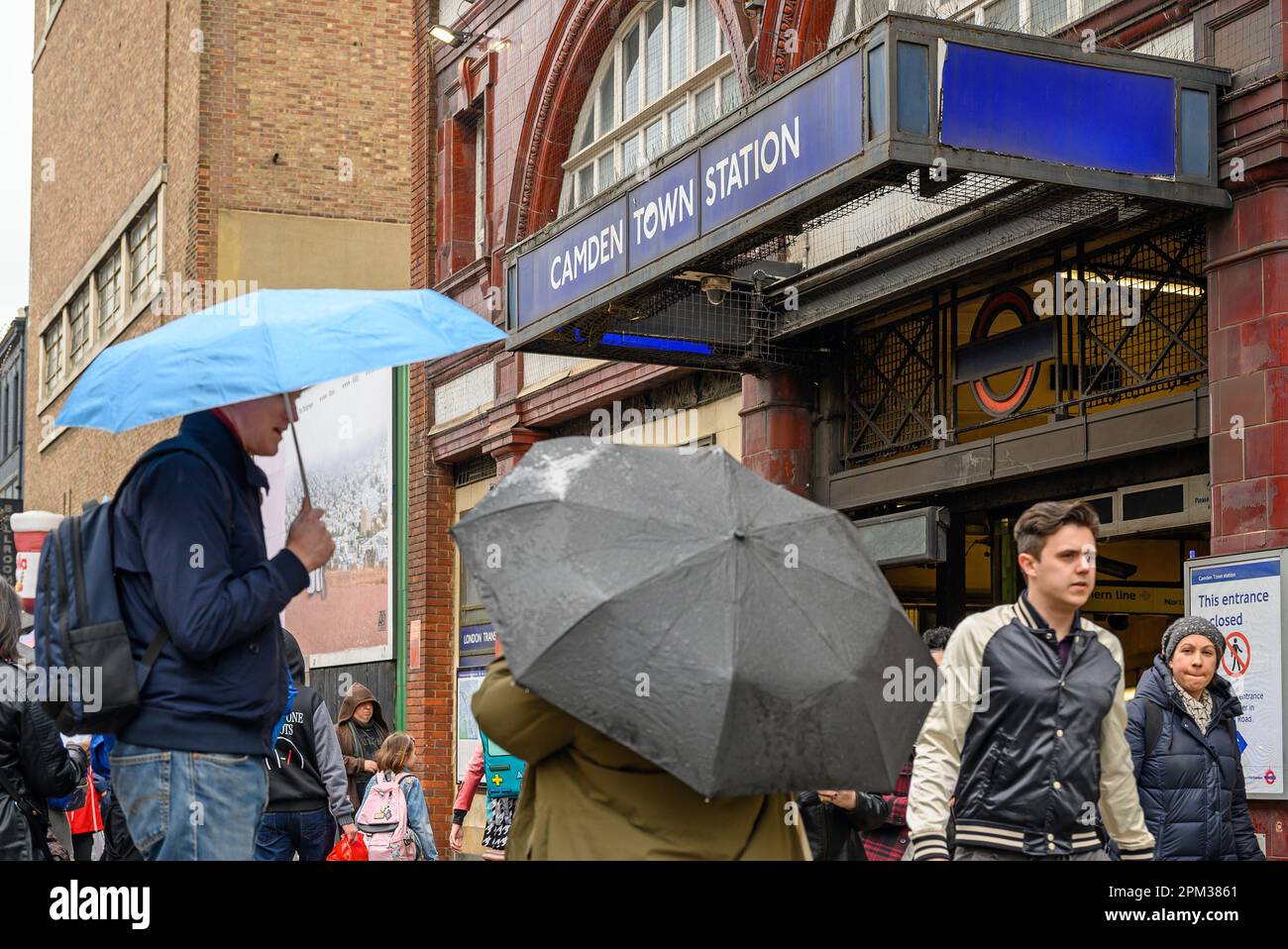 Camden Town, London: Outside Camden Town tube station on Camden High Street. People standing by the underground station in the rain. Stock Photo