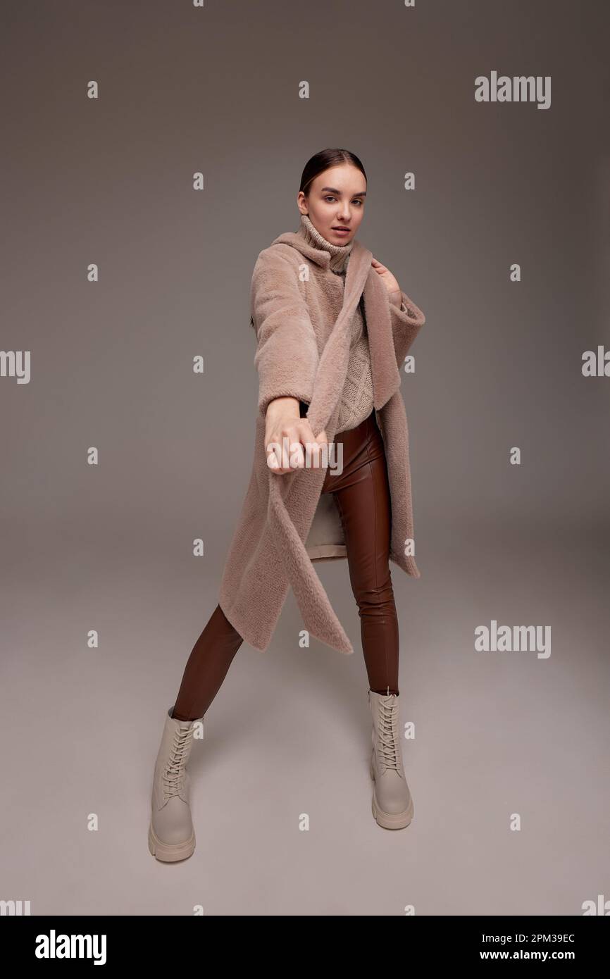 A beautiful business woman in a fur coat on a light background, a photo ...