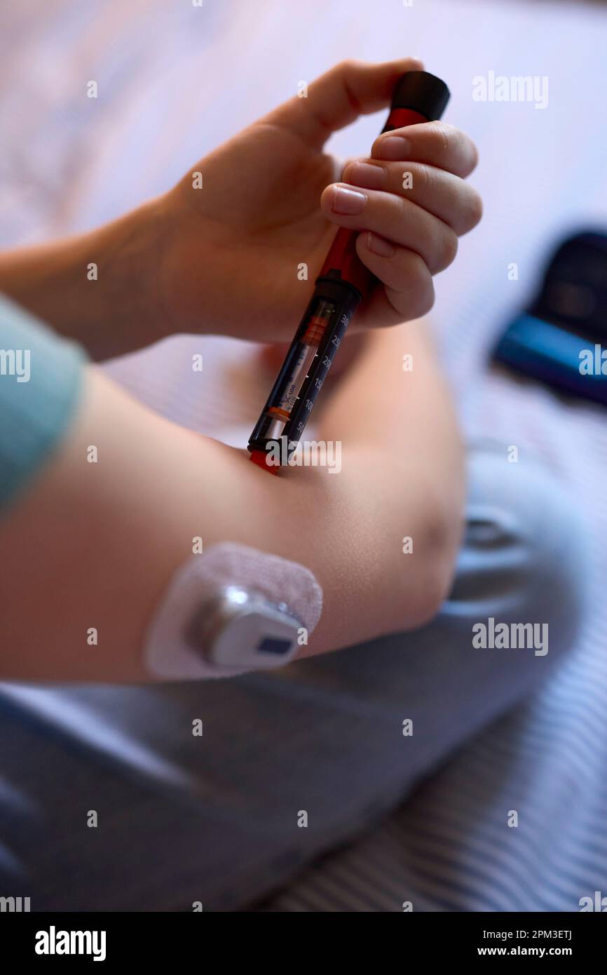 Close Up Of Diabetic Girl On Bed In At Home Using Insulin Pen To Measure To Check Blood Sugar Level Stock Photo