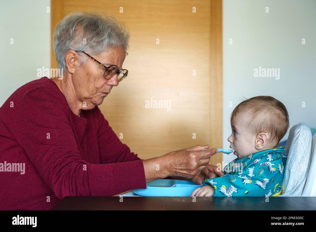 Grandmother feeding her baby grandson Stock Photo