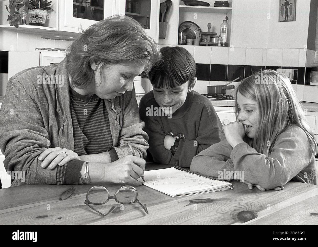 Woman helping children with homework / home schooling, UK 1990s Posed Stock Photo