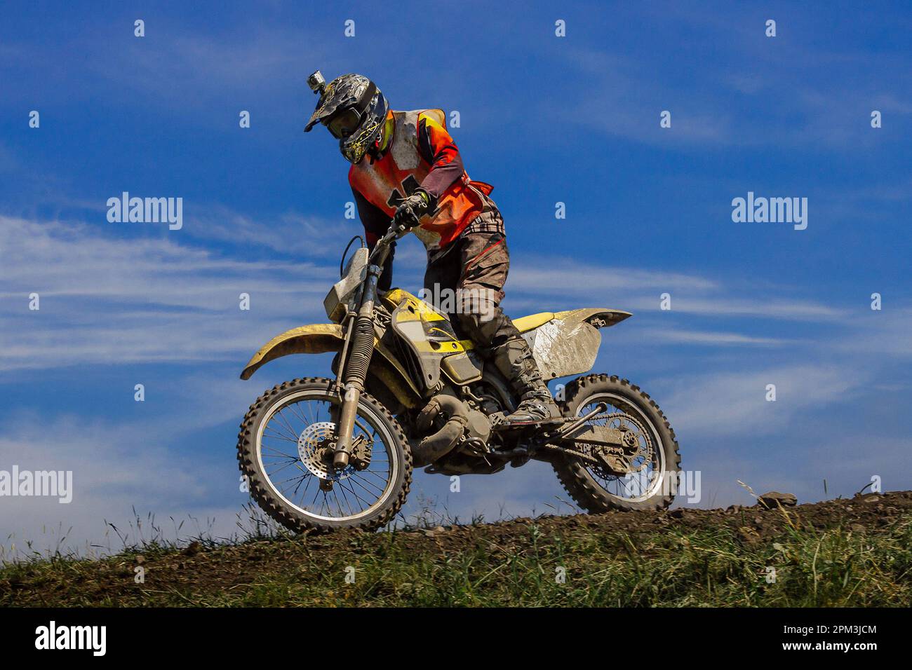 motocross rider riding off-road motorsport racing dusty trail on background blue sky Stock Photo