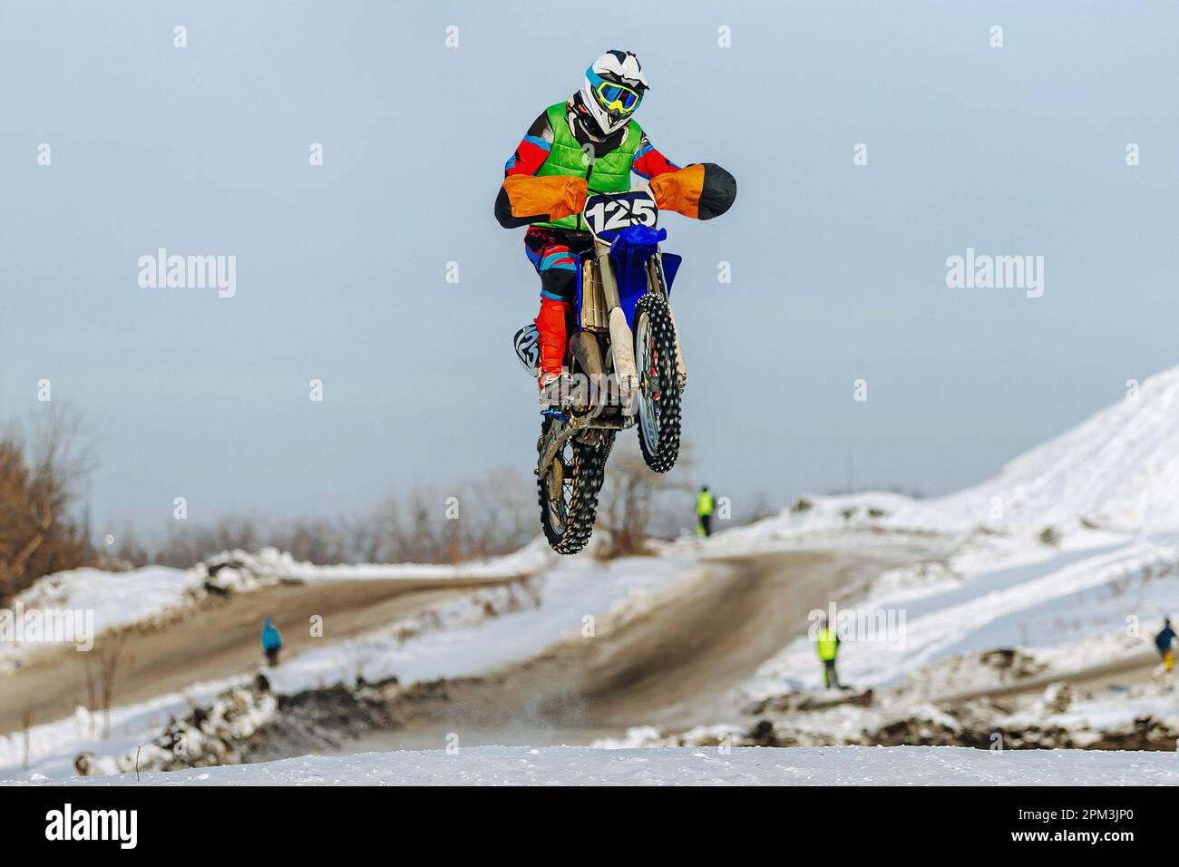 motocross rider jumping on snowy springboard, winter off-road motorcycle racing Stock Photo