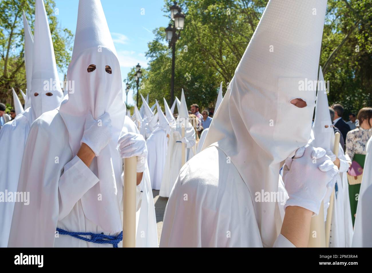 Seville Spain. Holy Week, Semana Santa. Palm Sunday. Participants wearing nazareno or penitential robe with a Capirote, a conical pointed hat. Stock Photo