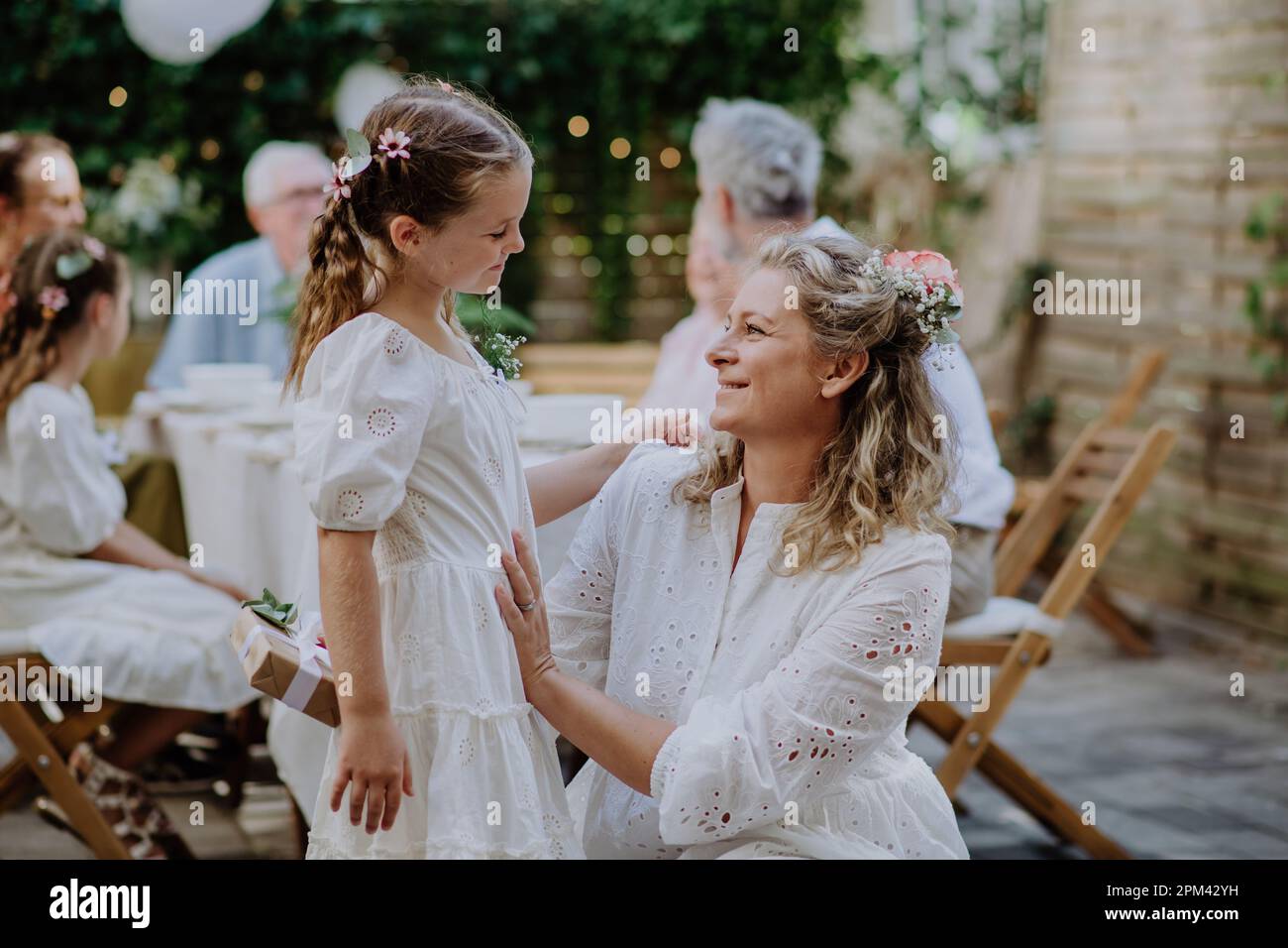 Little girl giving wedding gift to mature bride at wedding backyard ...