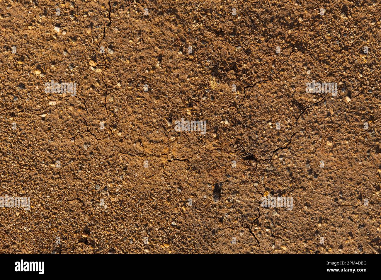 Brown background of cracked clay, sand, plaster interspersed with light ...