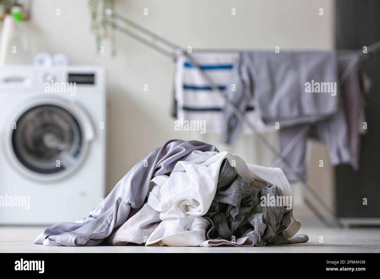 Stack of dirty clothes on floor in laundry room, closeup Stock Photo