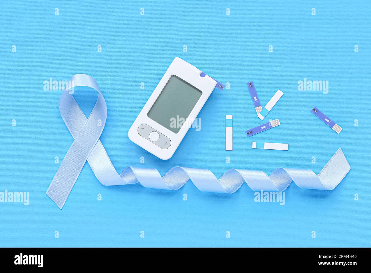 Awareness ribbon with glucometer and strips on blue background ...