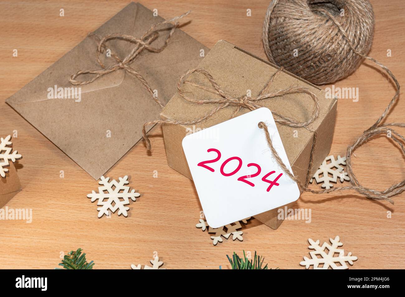 Happy New Year 2024. Eco-friendly gifts, homemade gifts, DIY. Gifts made of craft paper with the label 2024 on the table with wooden snowflakes, rope, Stock Photo