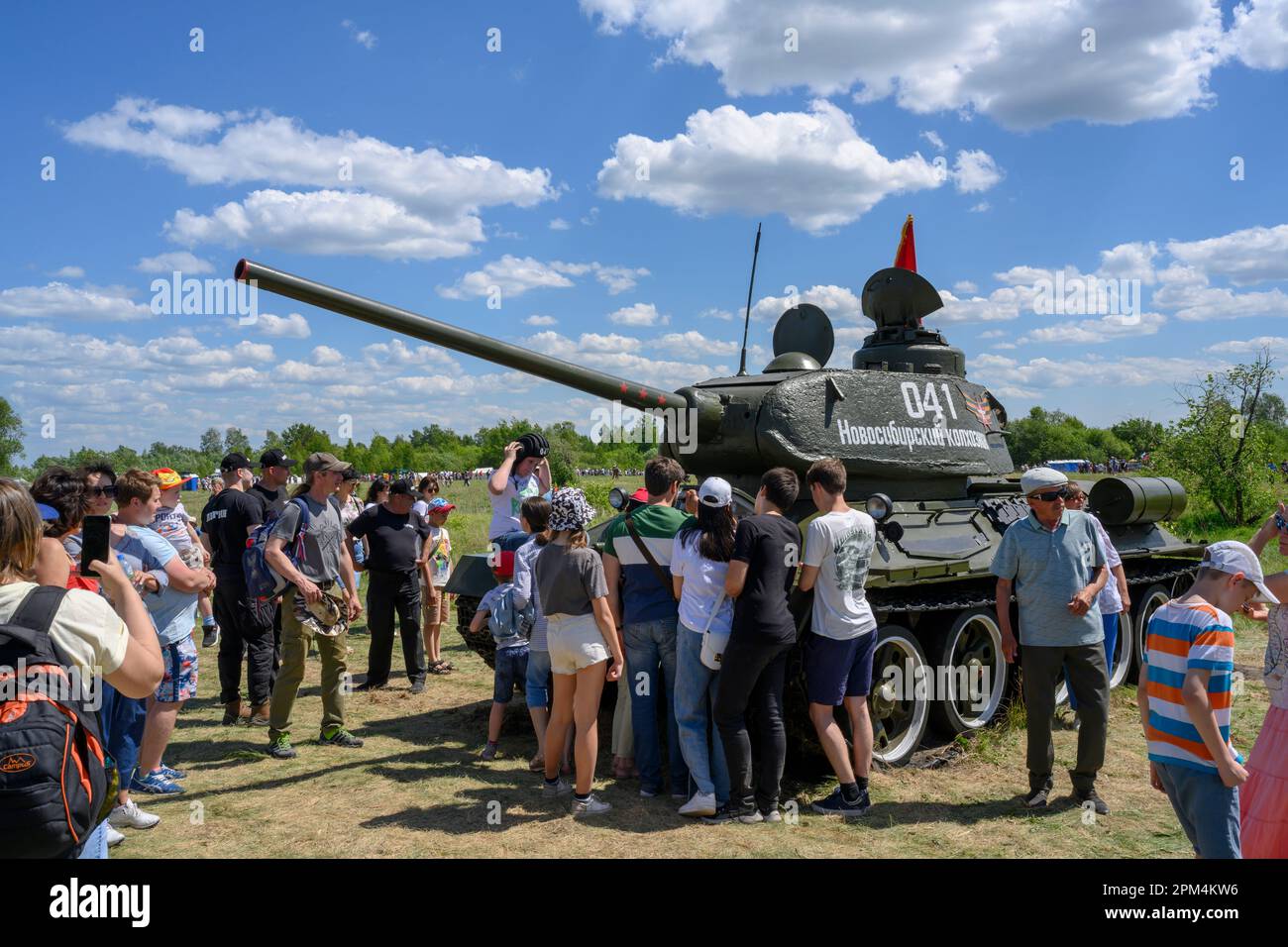 Tourists around a World War II battle tank in a forest clearing. The inscription on the tank: 'Novosibirsk farmer' Stock Photo