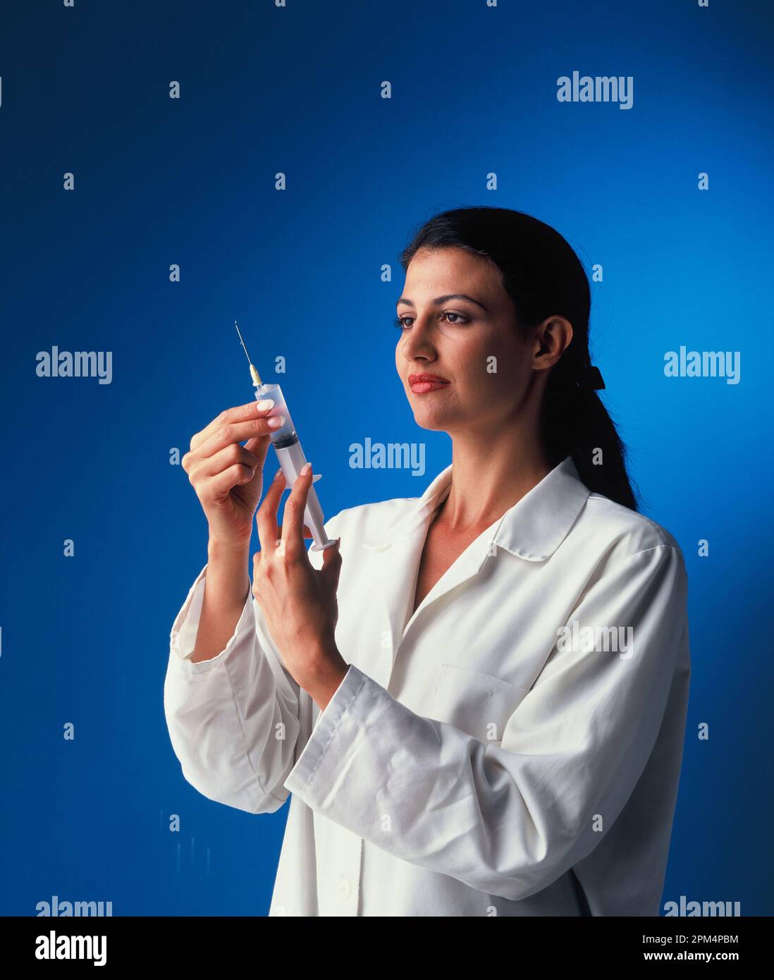 Female medical professional preparing hypodermic syringe. Stock Photo