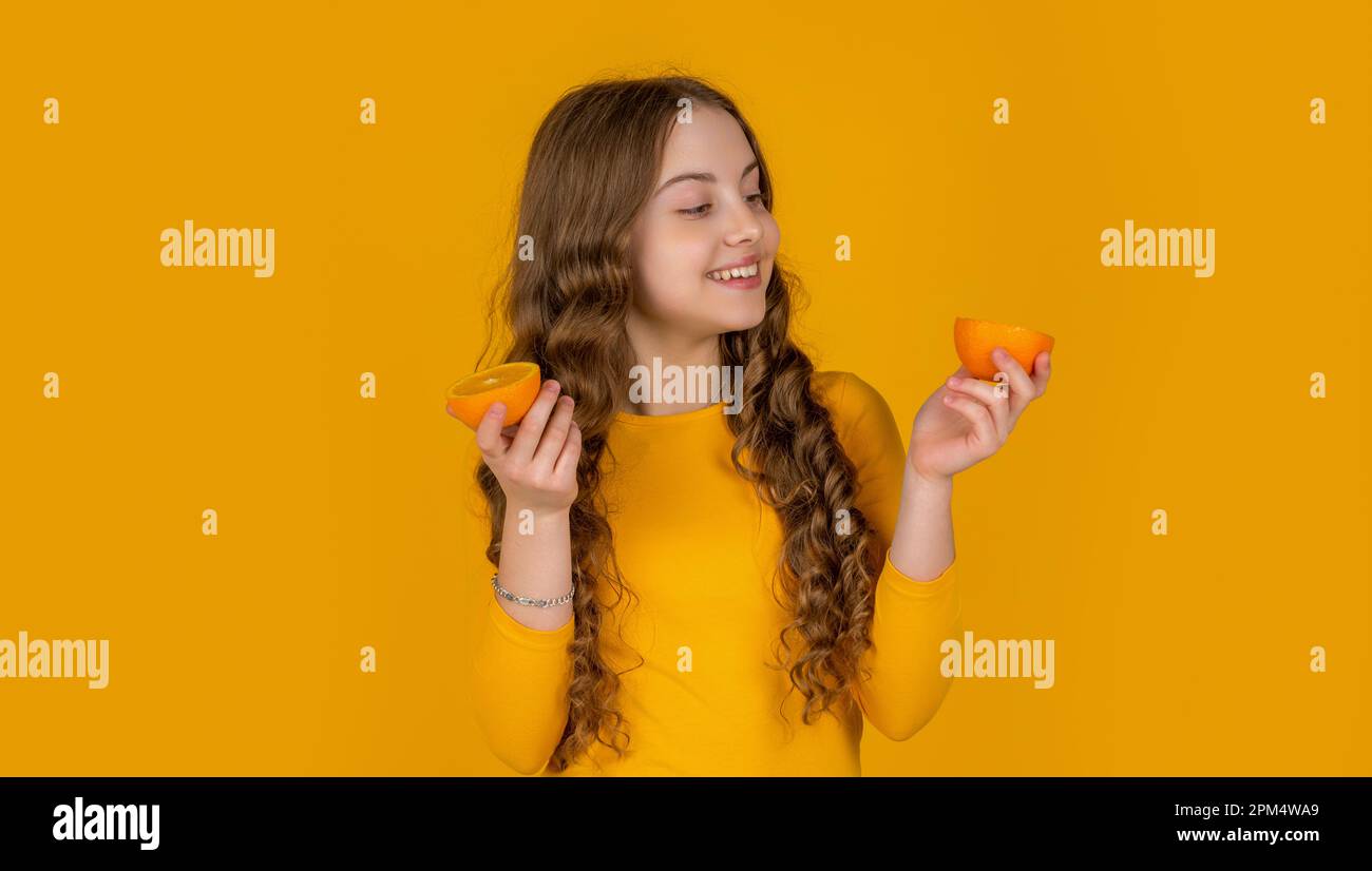 positive teen girl hold orange fruit on yellow background Stock Photo ...