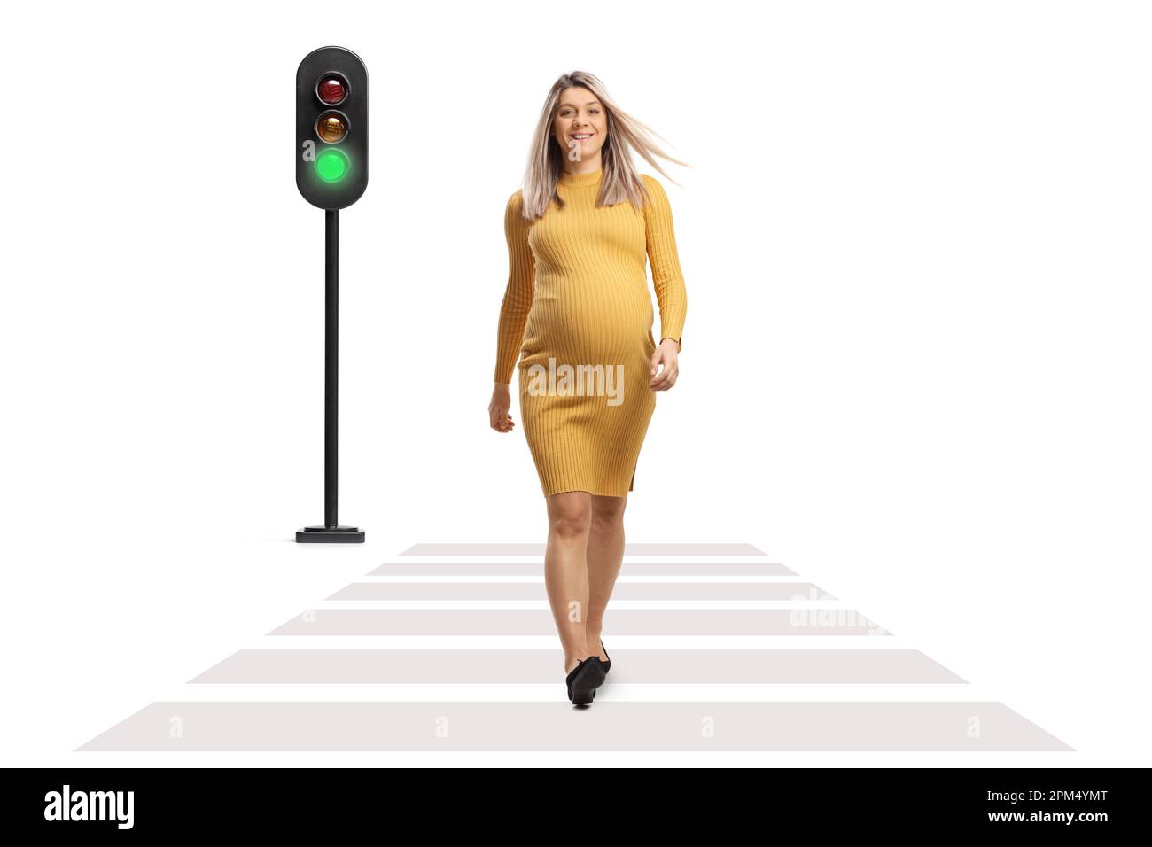 Full length portrait of a pregnant woman in a yellow dress crossing a street at a pedestrian crossing isolated on white background Stock Photo