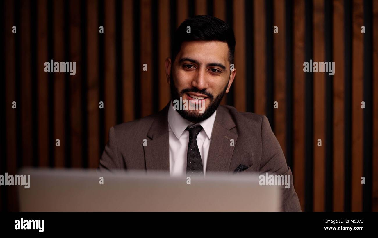 Handsome smiling latin man using laptop computer explaining something having video call. Stock Photo