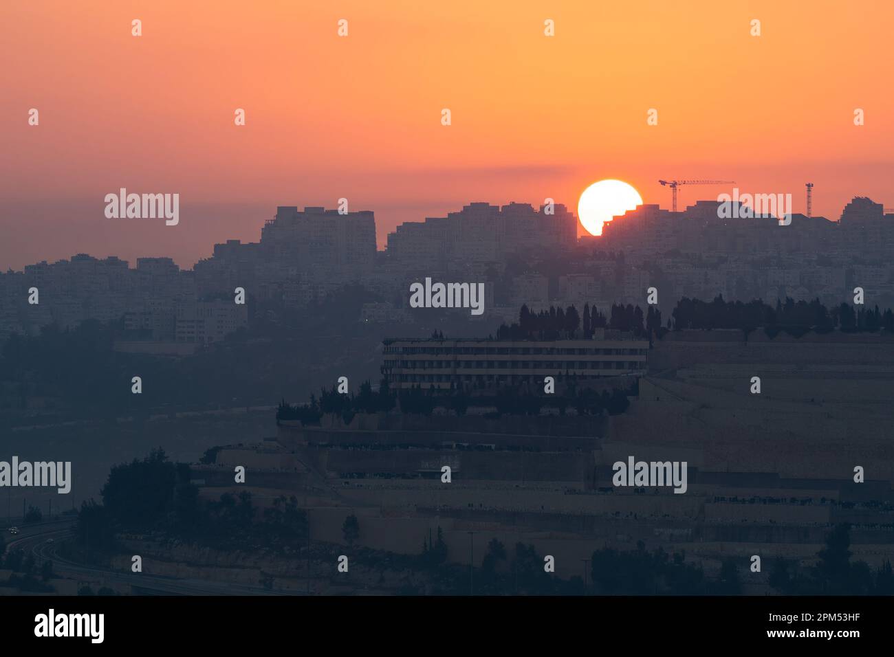 The sun rises in a clear sky, over the northern neighborhoods of Jerusalem, Israel, and the Givat Shaul cemetery. Stock Photo