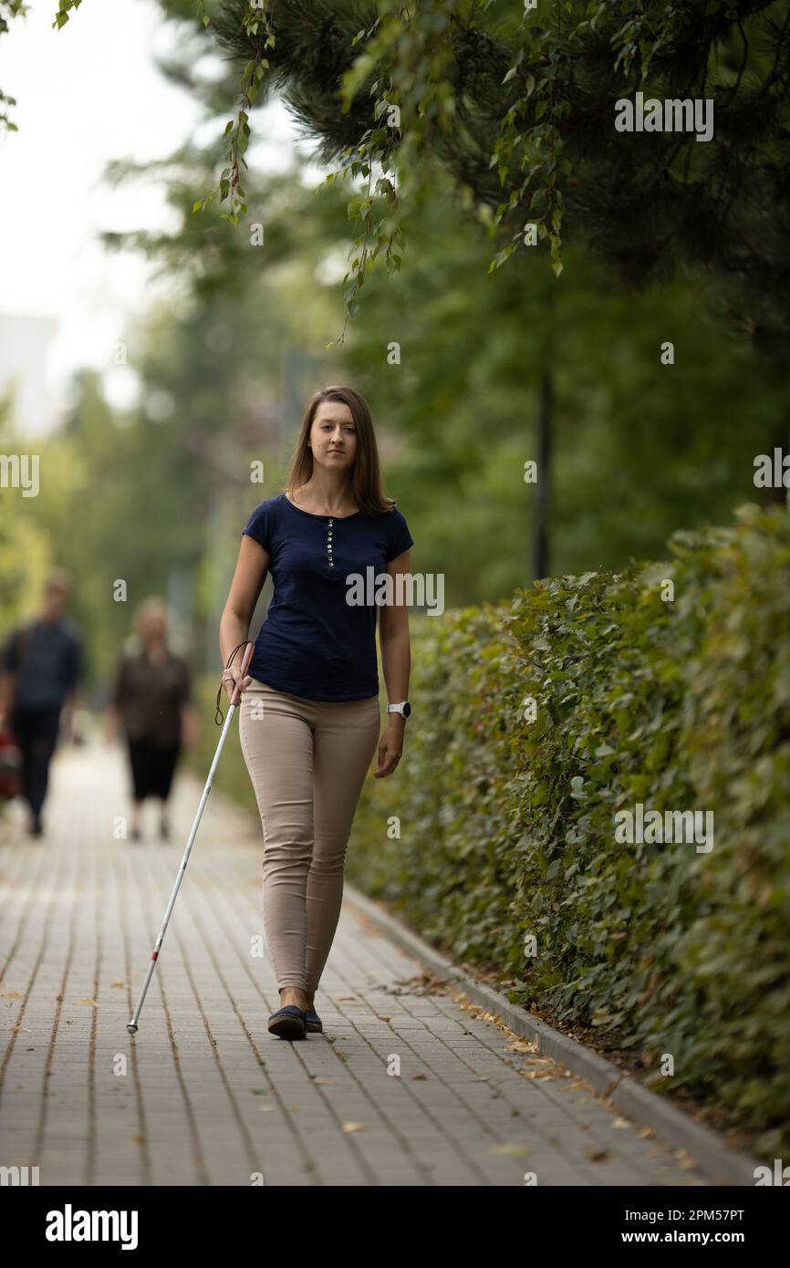Young woman with vision impairment walking on city streets, using her
