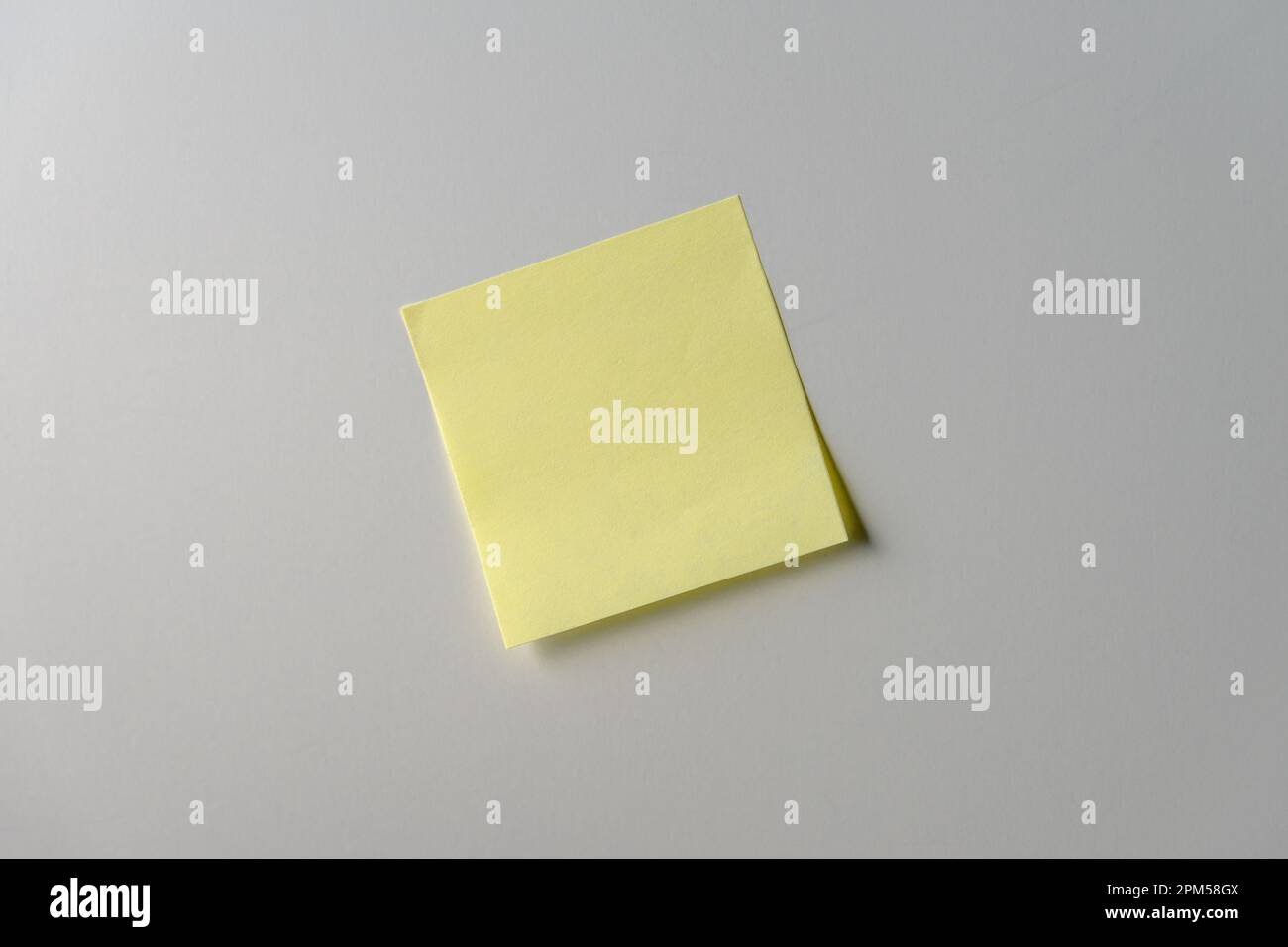 Yellow note paper on white background. Copy space. Close up. Stock Photo