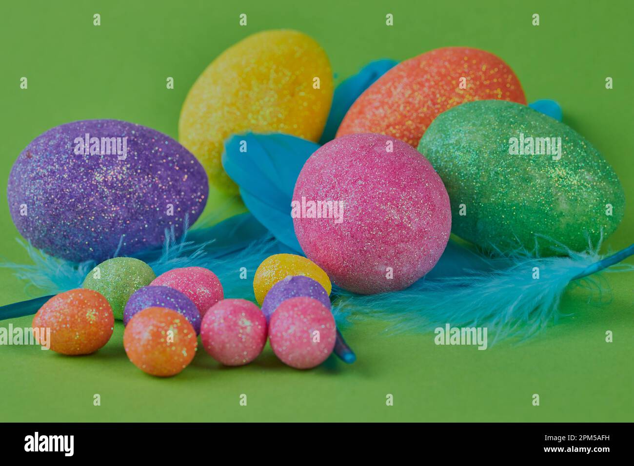 Colored Easter eggs and feathers on a green background. Stock Photo