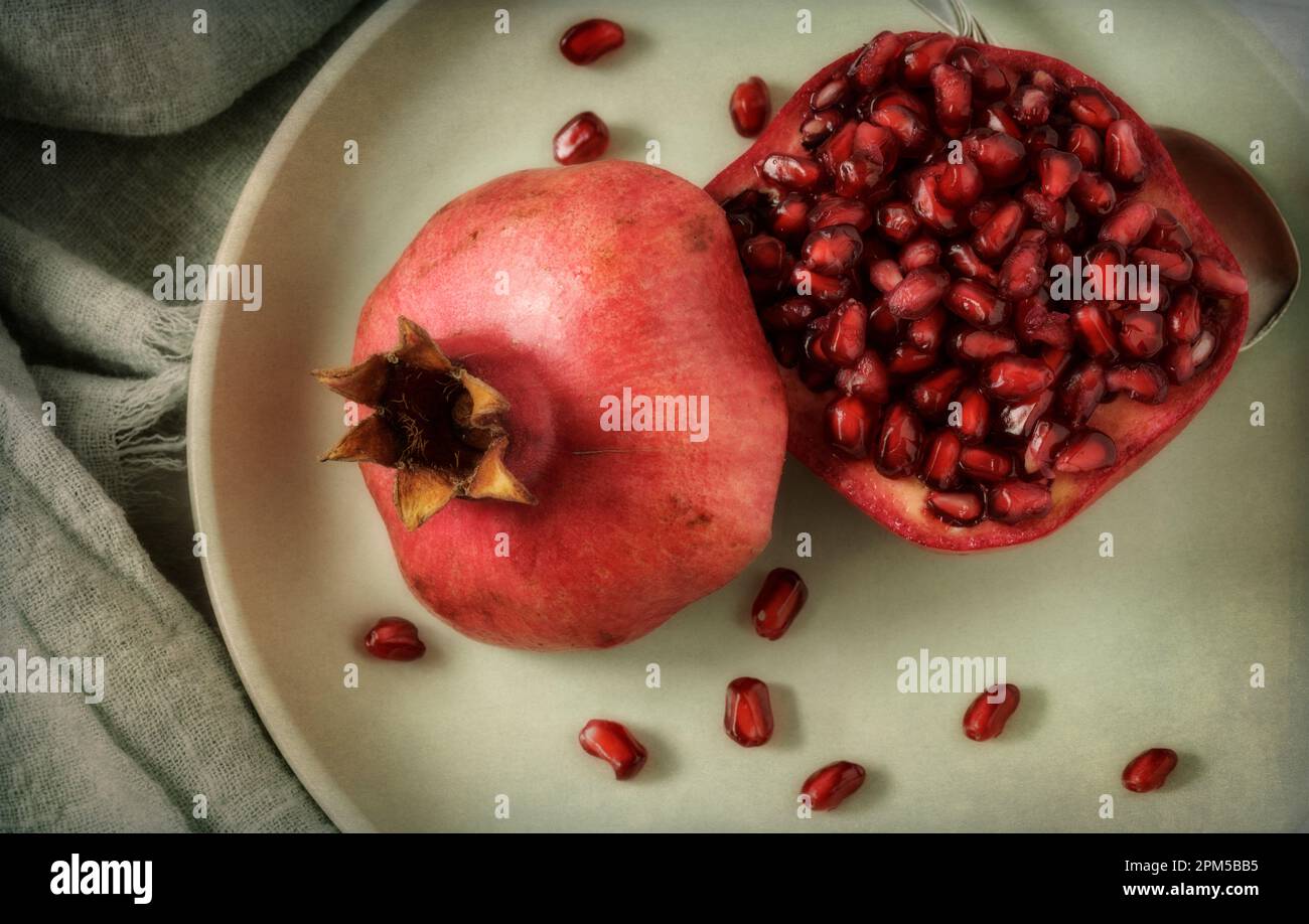 One cut pomegranate on green plate Stock Photo