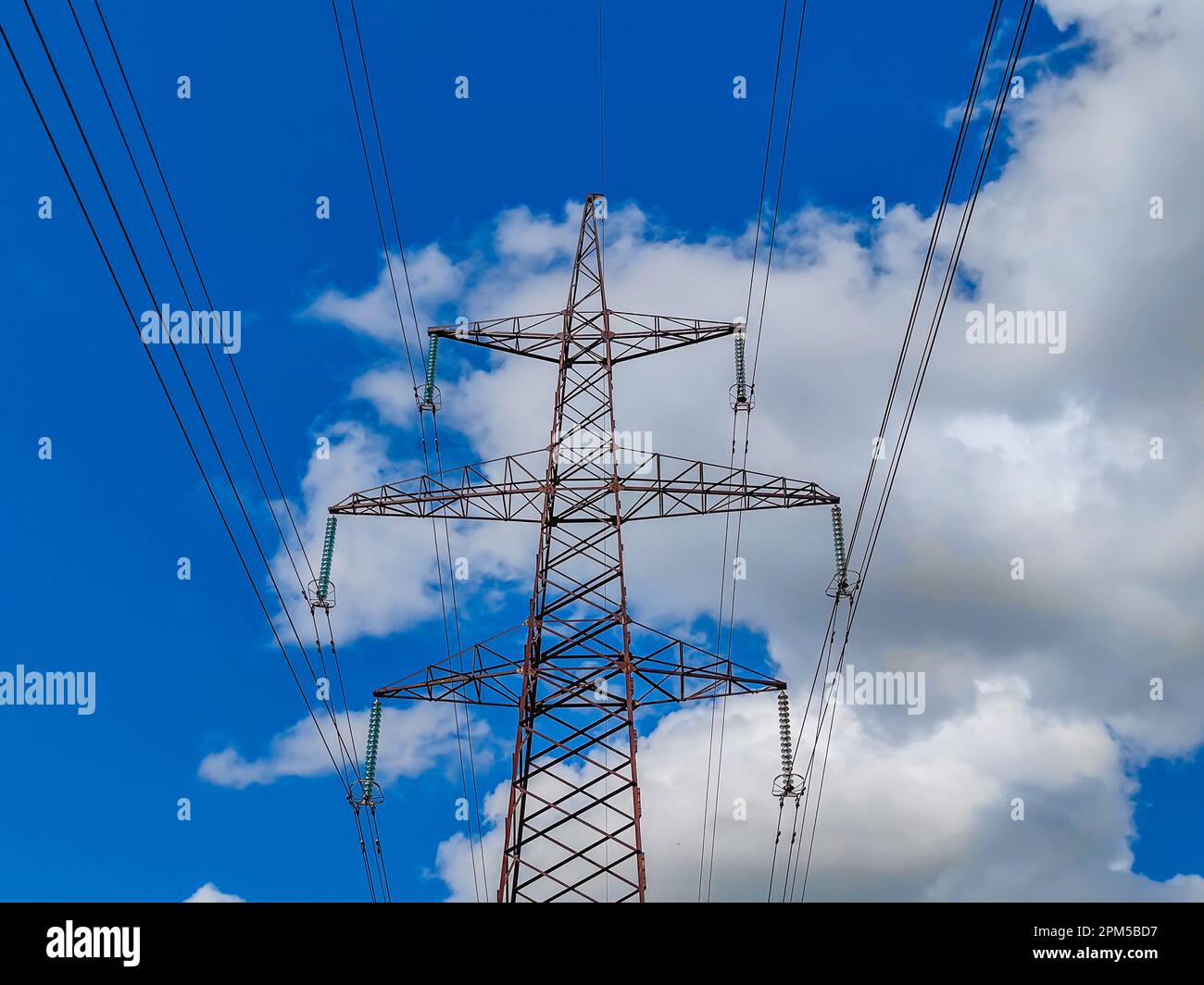 High voltage line poles and wires with blue sky and white clouds ...
