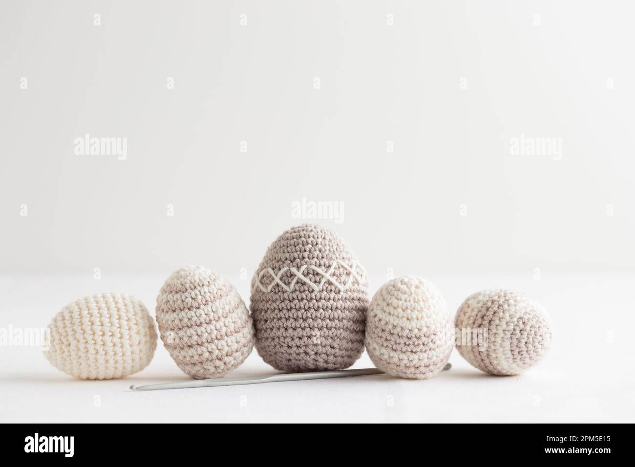 Row of cute striped pattern crocheted eggs, pastel color on a white Stock Photo