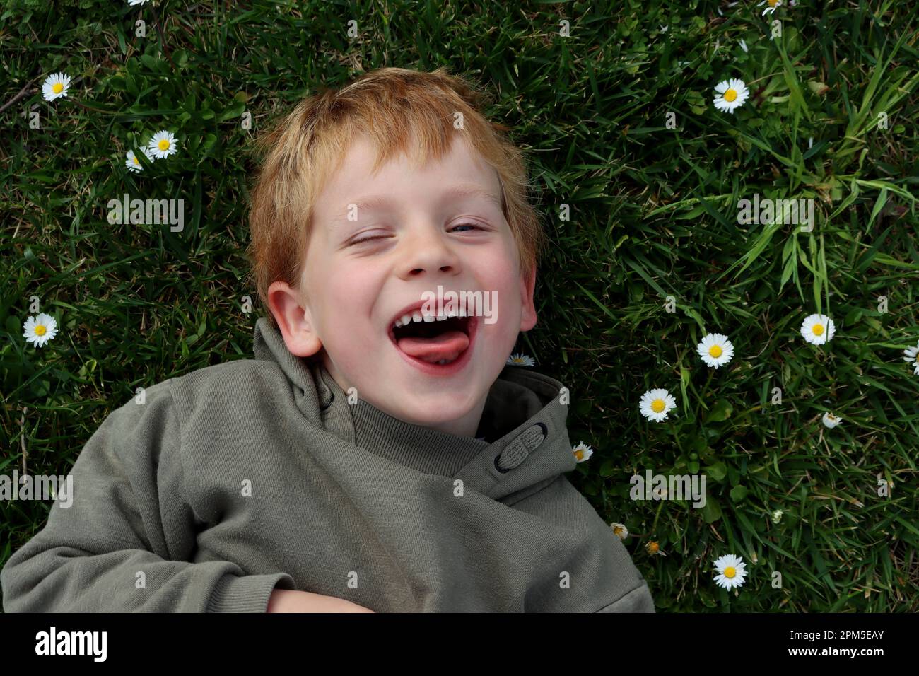 The blond boy narrowed his eyes and shows his tongue. Stock Photo