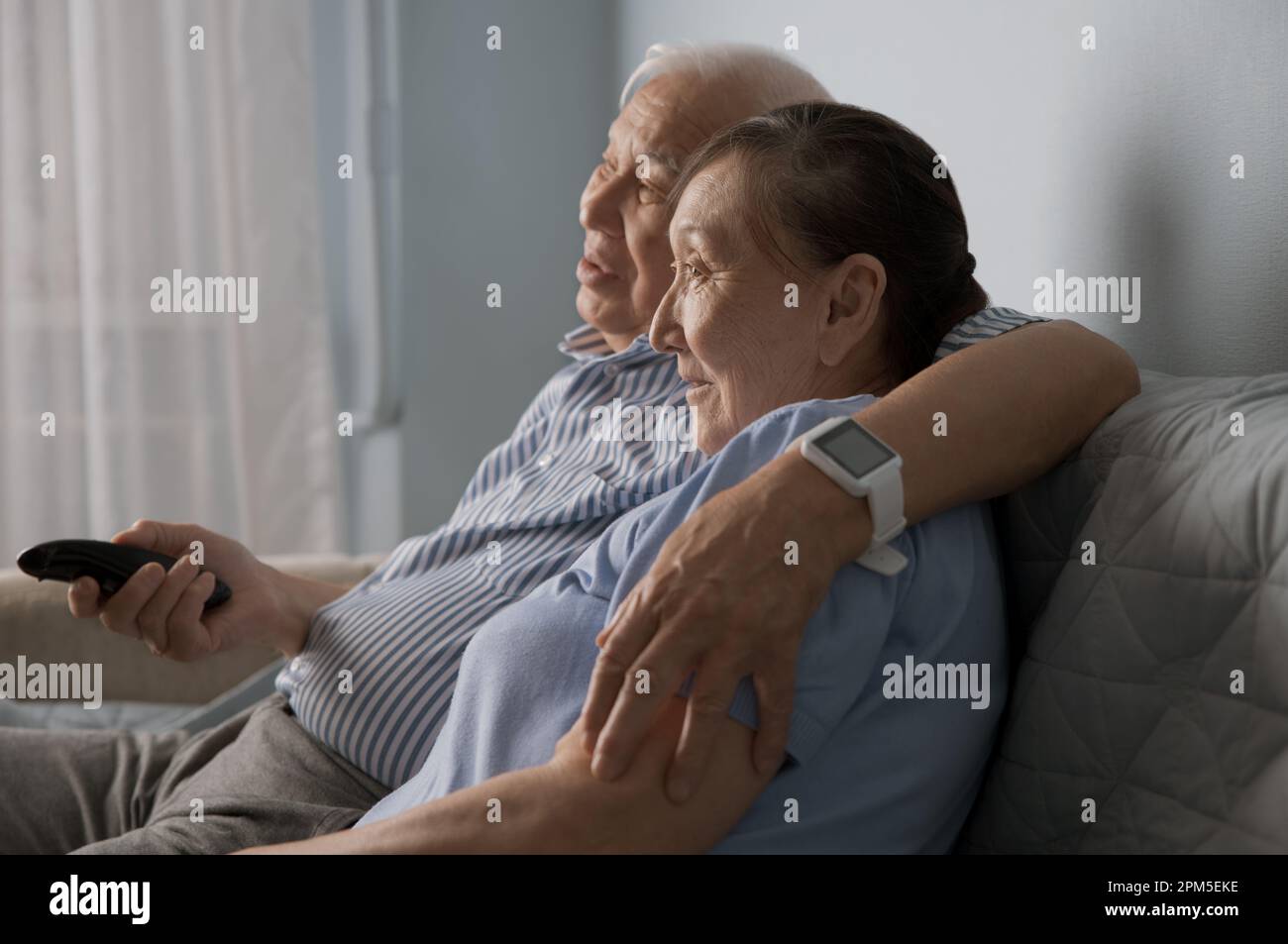 Senior couple watching tv and using remote control at home Stock Photo