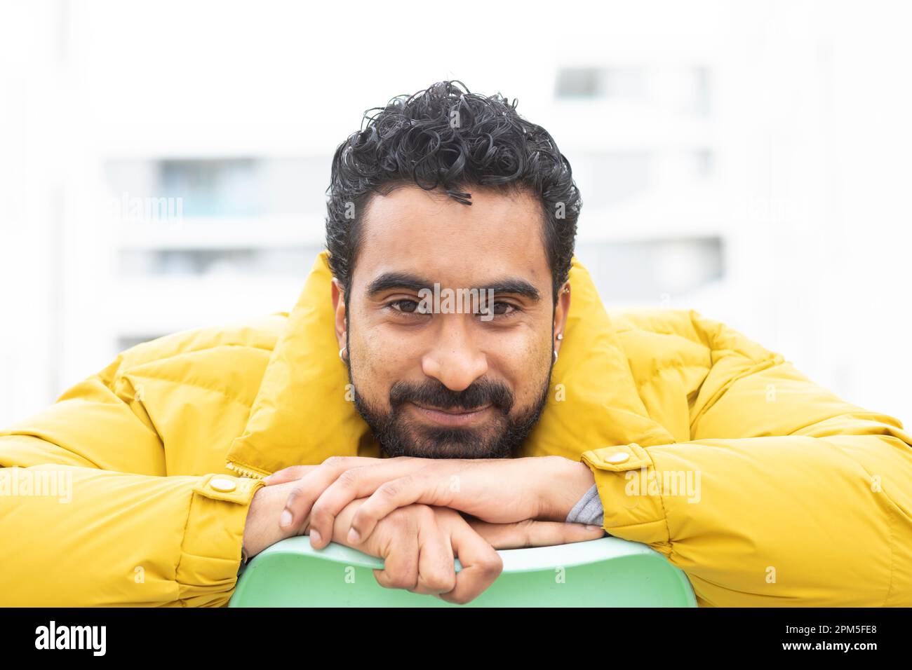 young man with yellow jacket and green chair Stock Photo