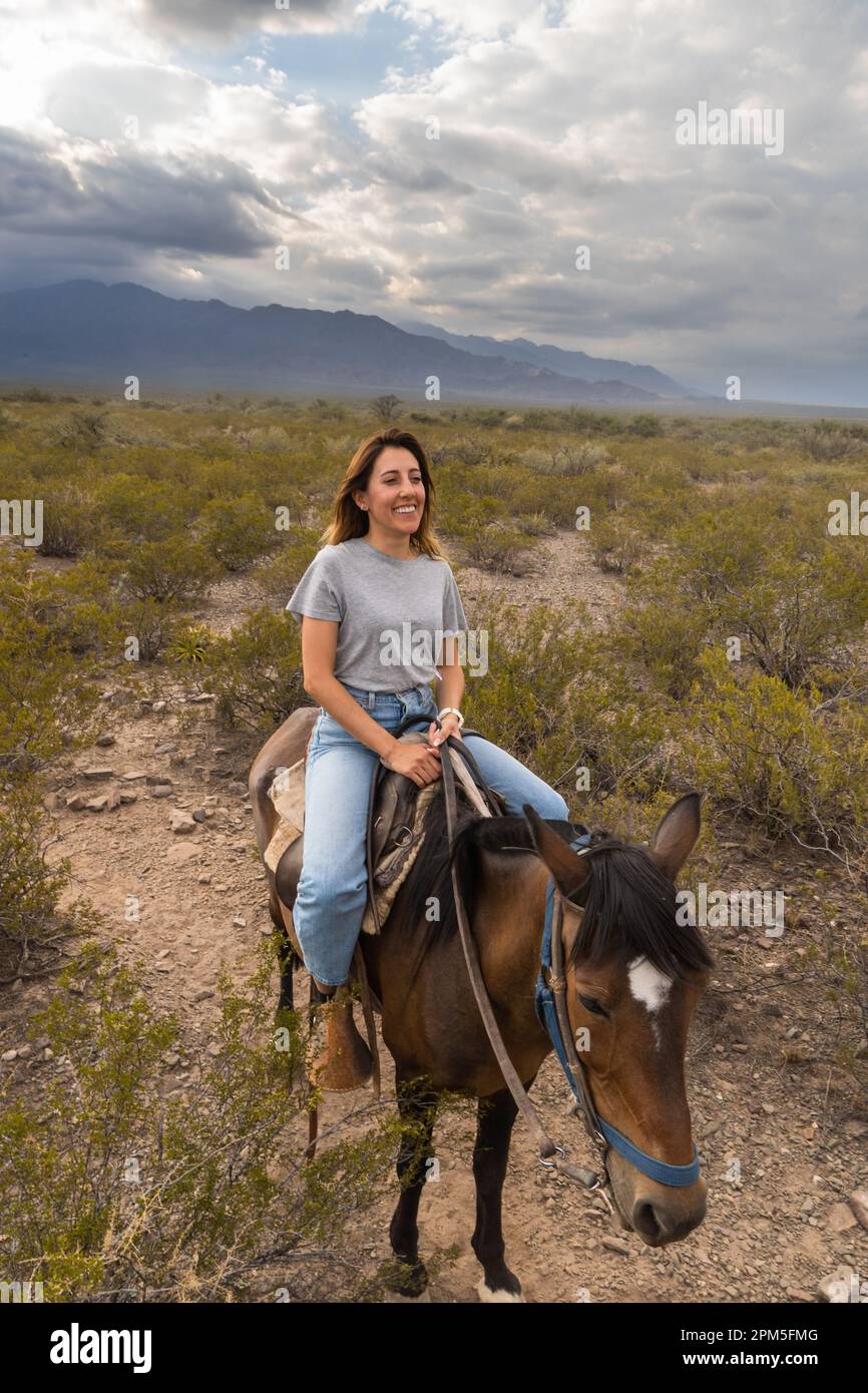 Woman smiling riding a horse in mountains of mendoza argentina Stock Photo
