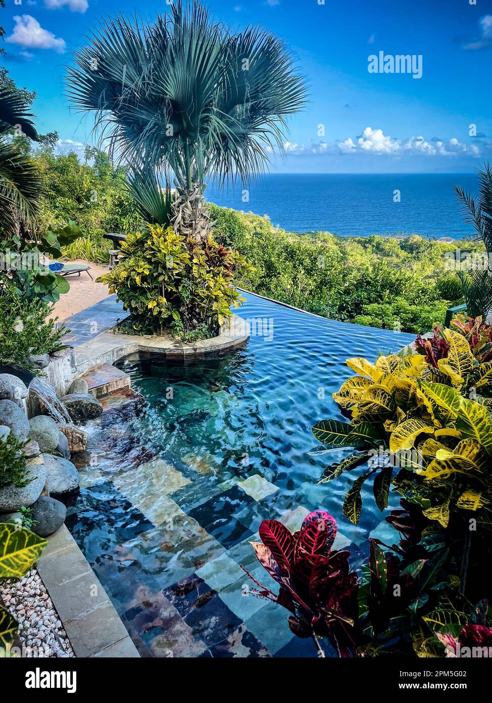 Beautiful swimming pool in tropical setting with view of ocean Stock Photo