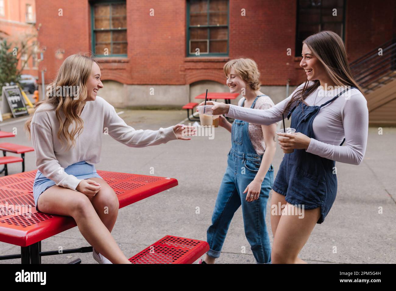 Friends bringing woman friend coffee outside in the city Stock Photo