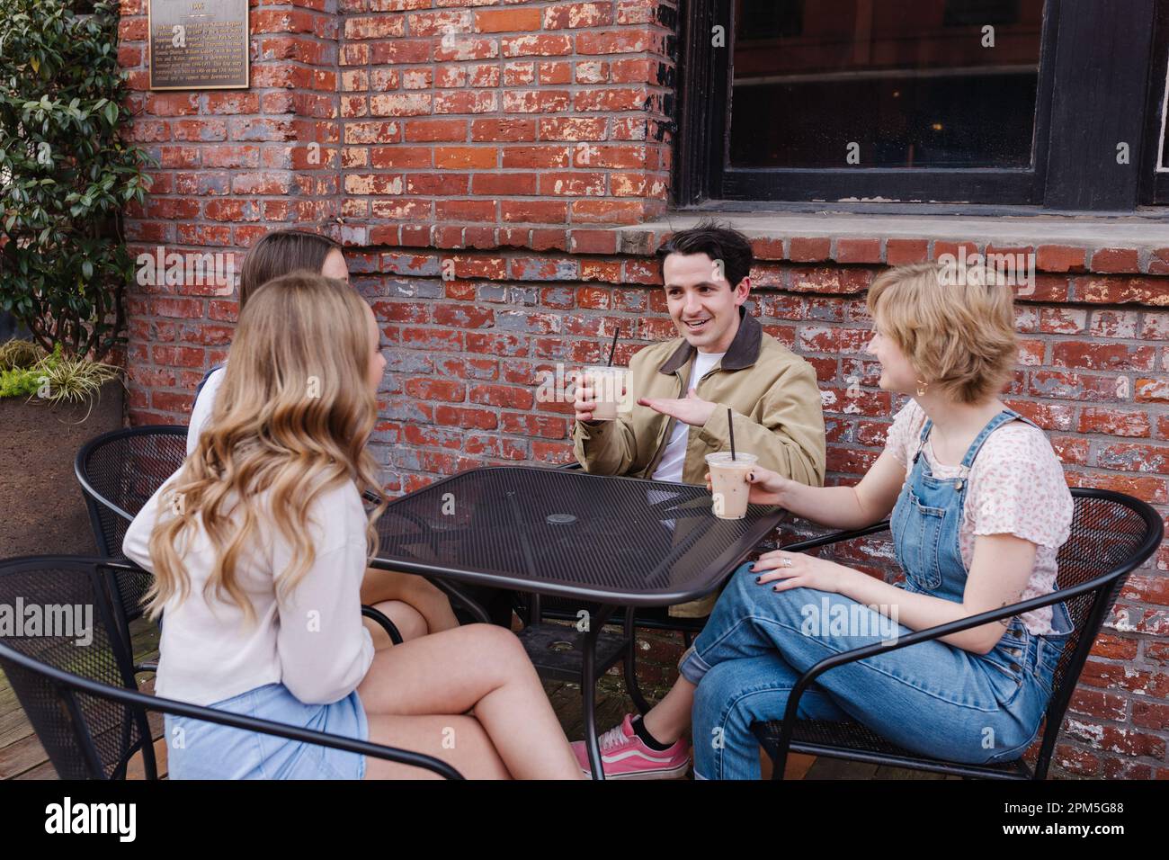 Group of friends talking happily at outside table downtown Stock Photo