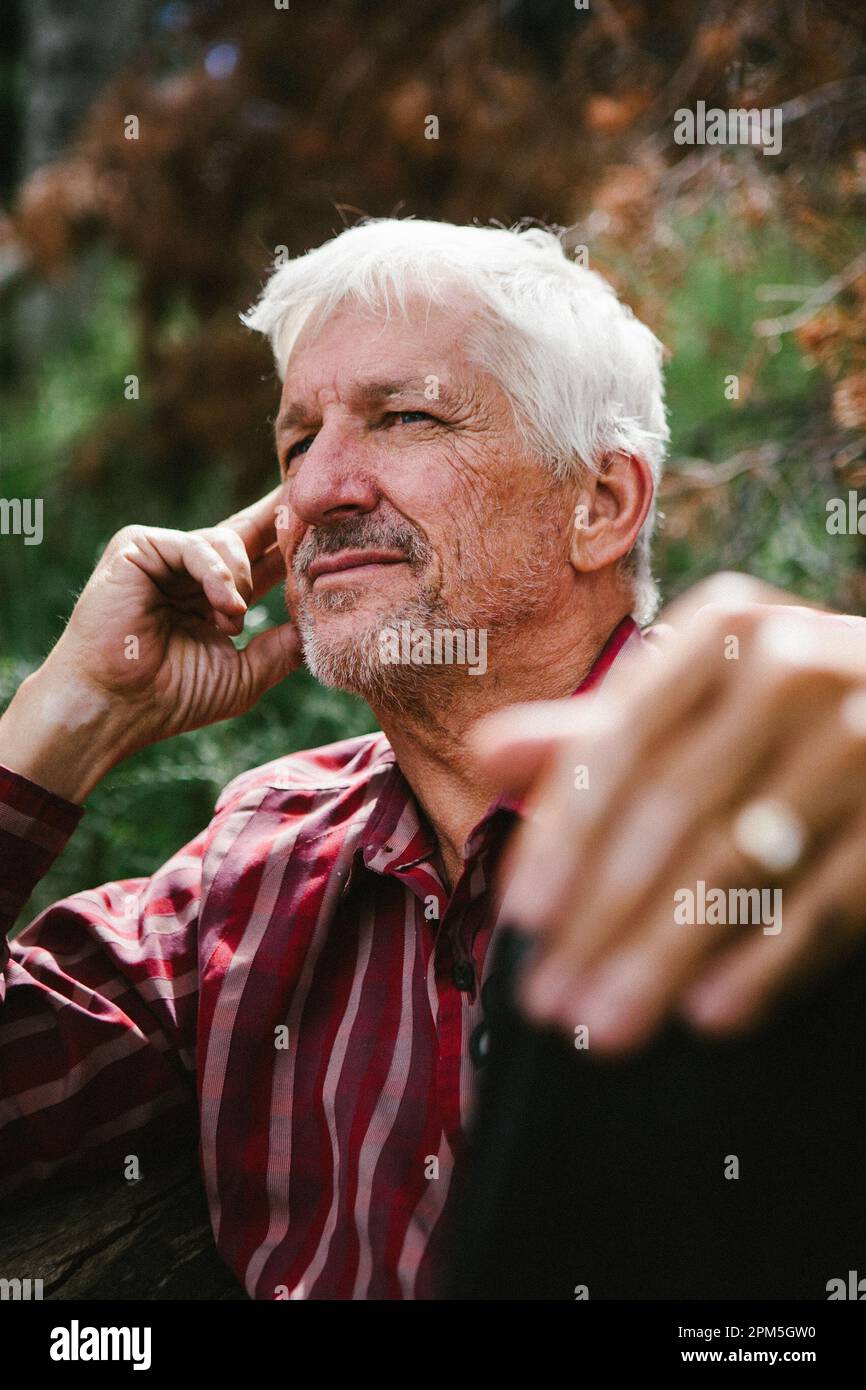 White haired man looks contemplative on a sunny summer day Stock Photo