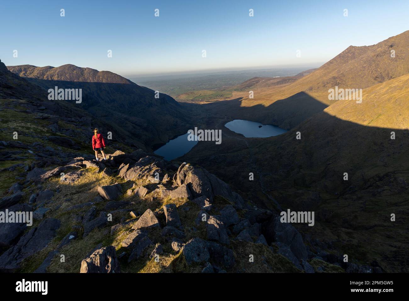 Woman on top of mountain with two lakes in the background Stock Photo