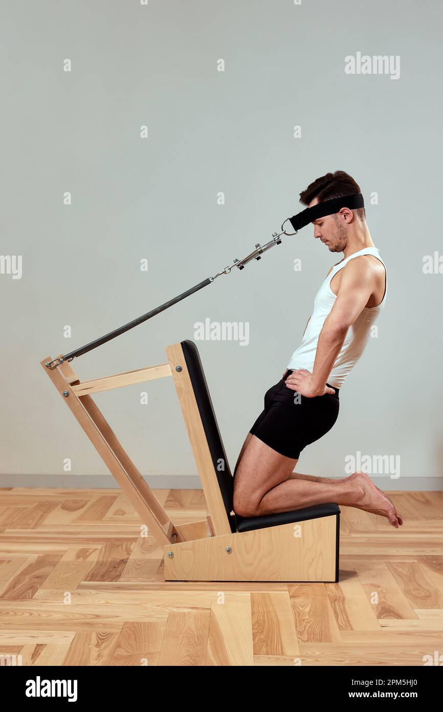 A man does exercises for the neck on reformers during Pilates, a young