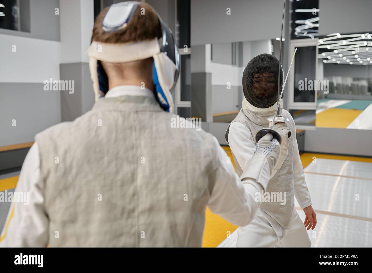 Pair of fencing partners fighting with rapiers practicing attack and