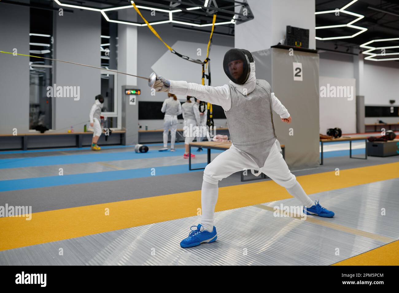 Young fencer practicing attack in training room after lesson. Swordsman
