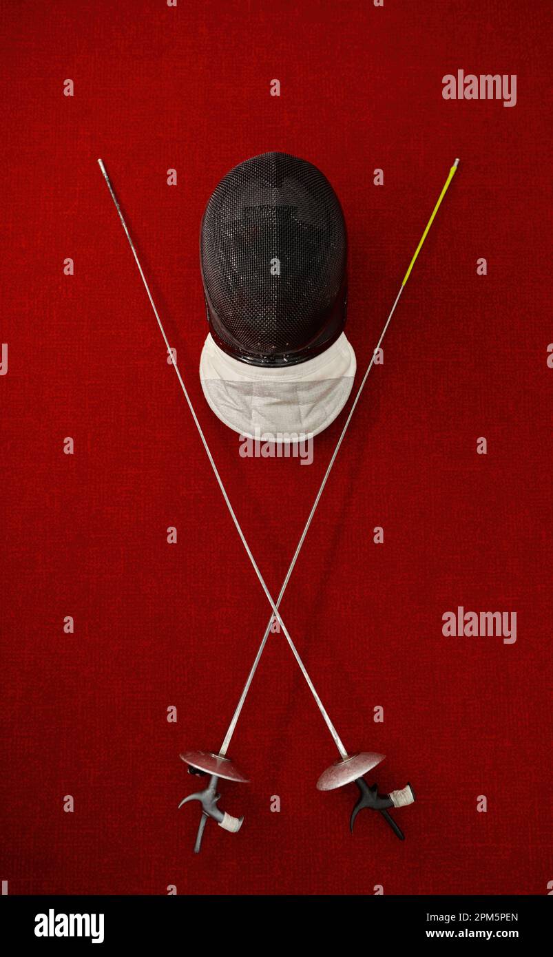 Fencing equipment concept, crossed swords and protective helmet with