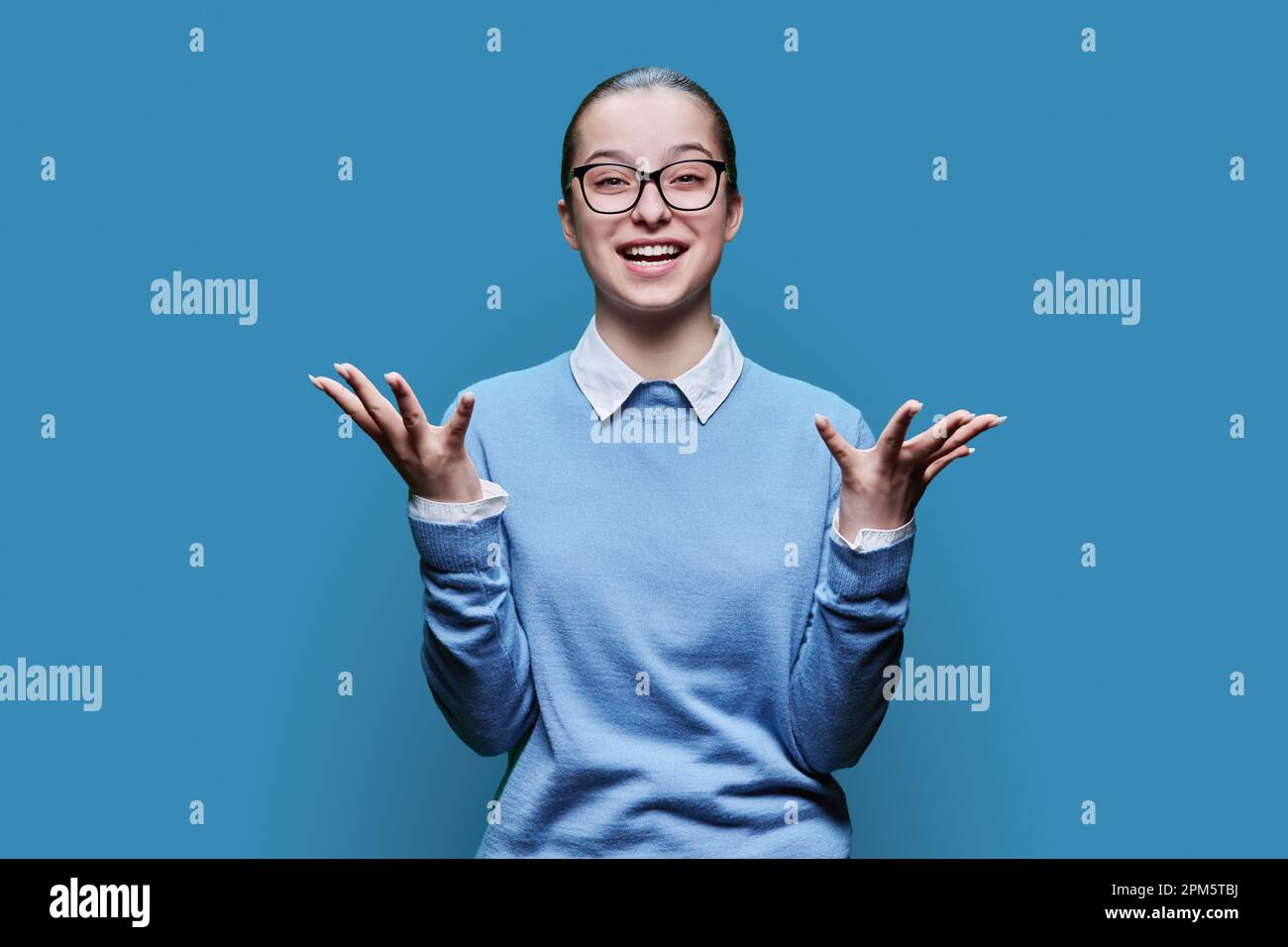 Happy joyful teenage girl on blue studio background Stock Photo - Alamy