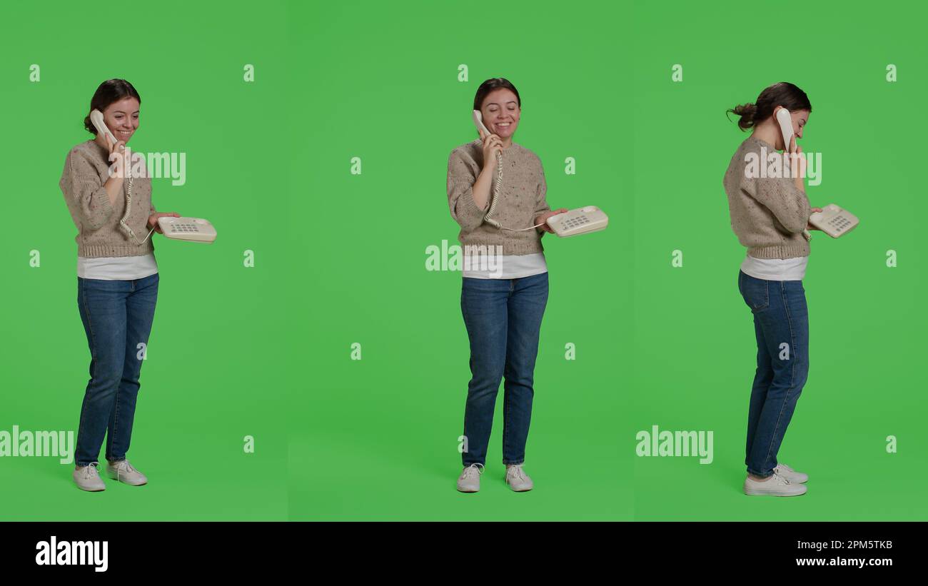 Female model answering landline phone call on telephone line, standing