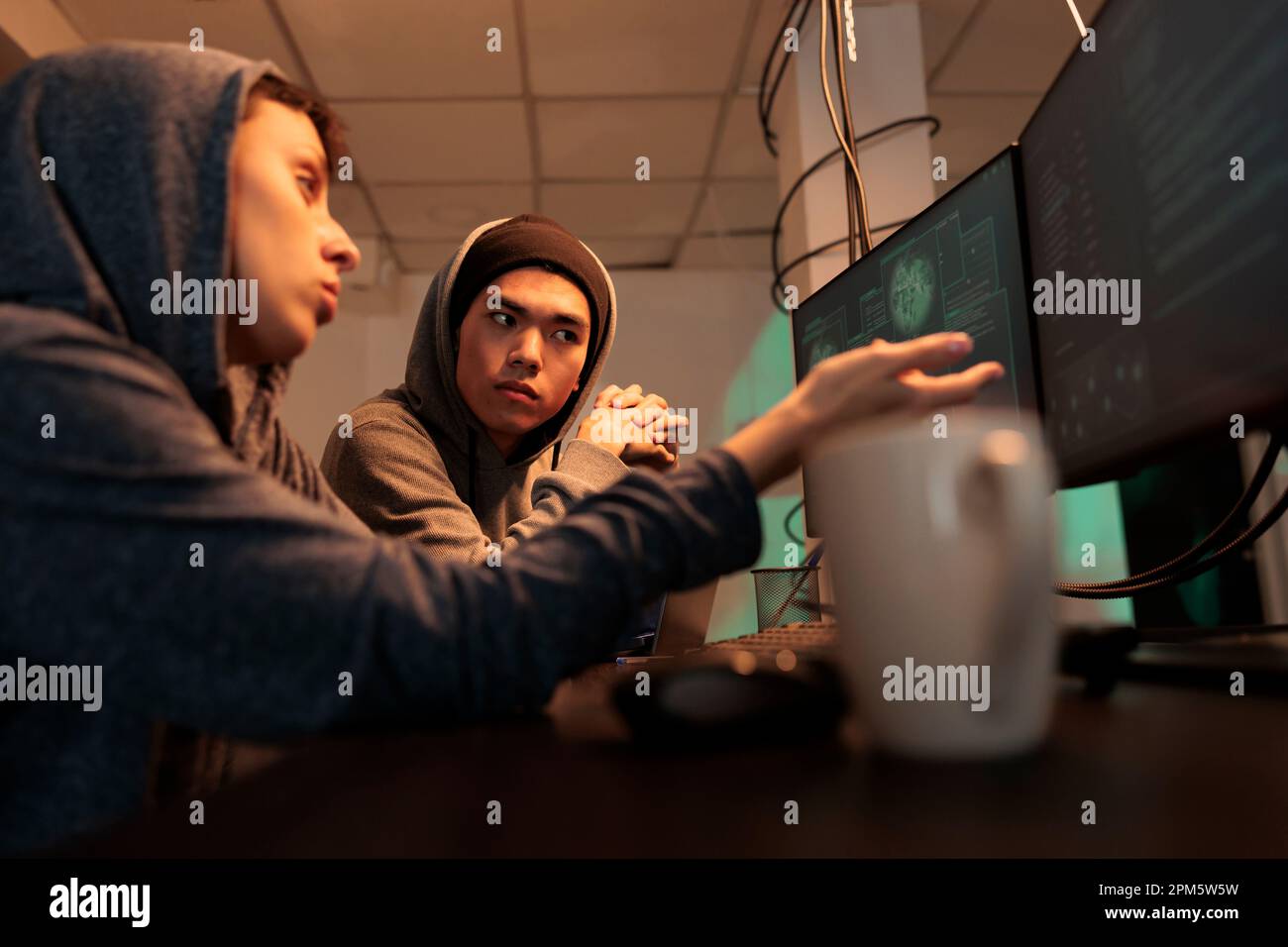 Hackers planning cyberattack, discussing malicious software code, criminals breaking into database, stealing information. Internet fraud, scammers hacking computer system at night time Stock Photo
