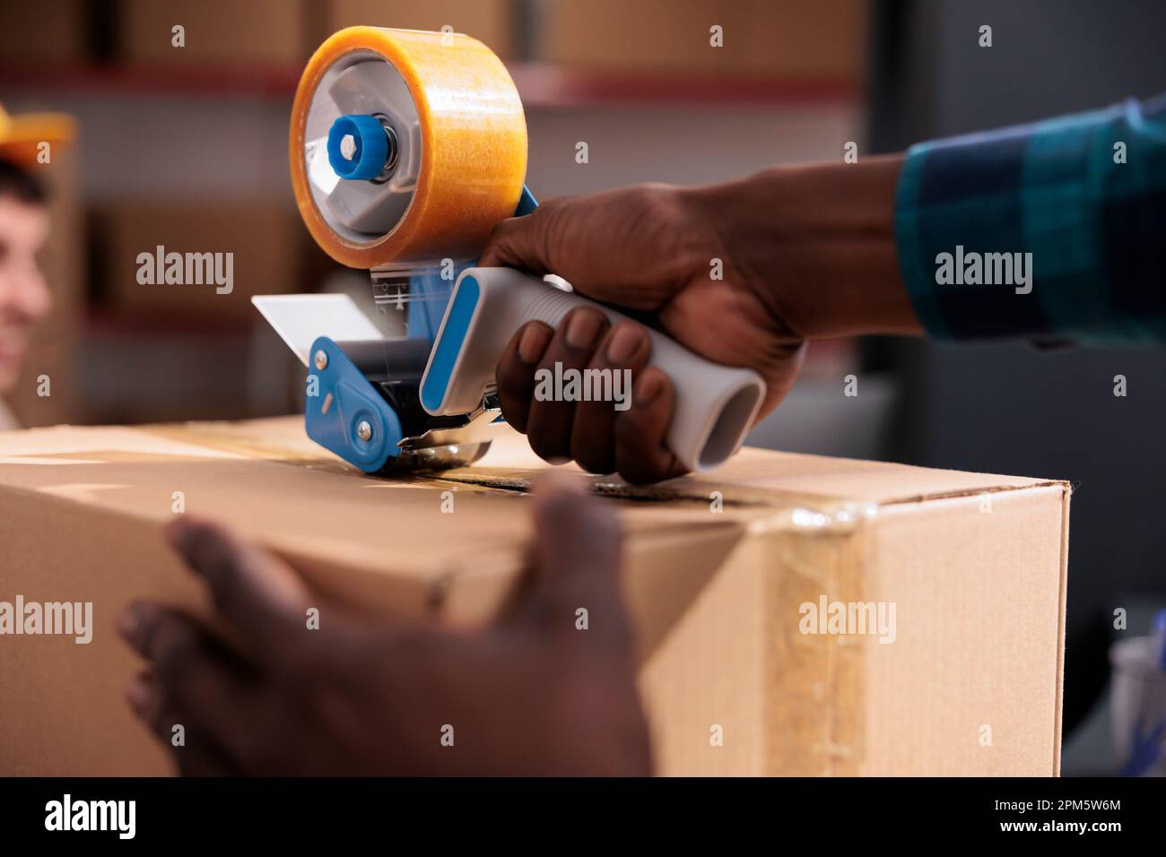 African american storehouse employee arms wrapping cardboard package