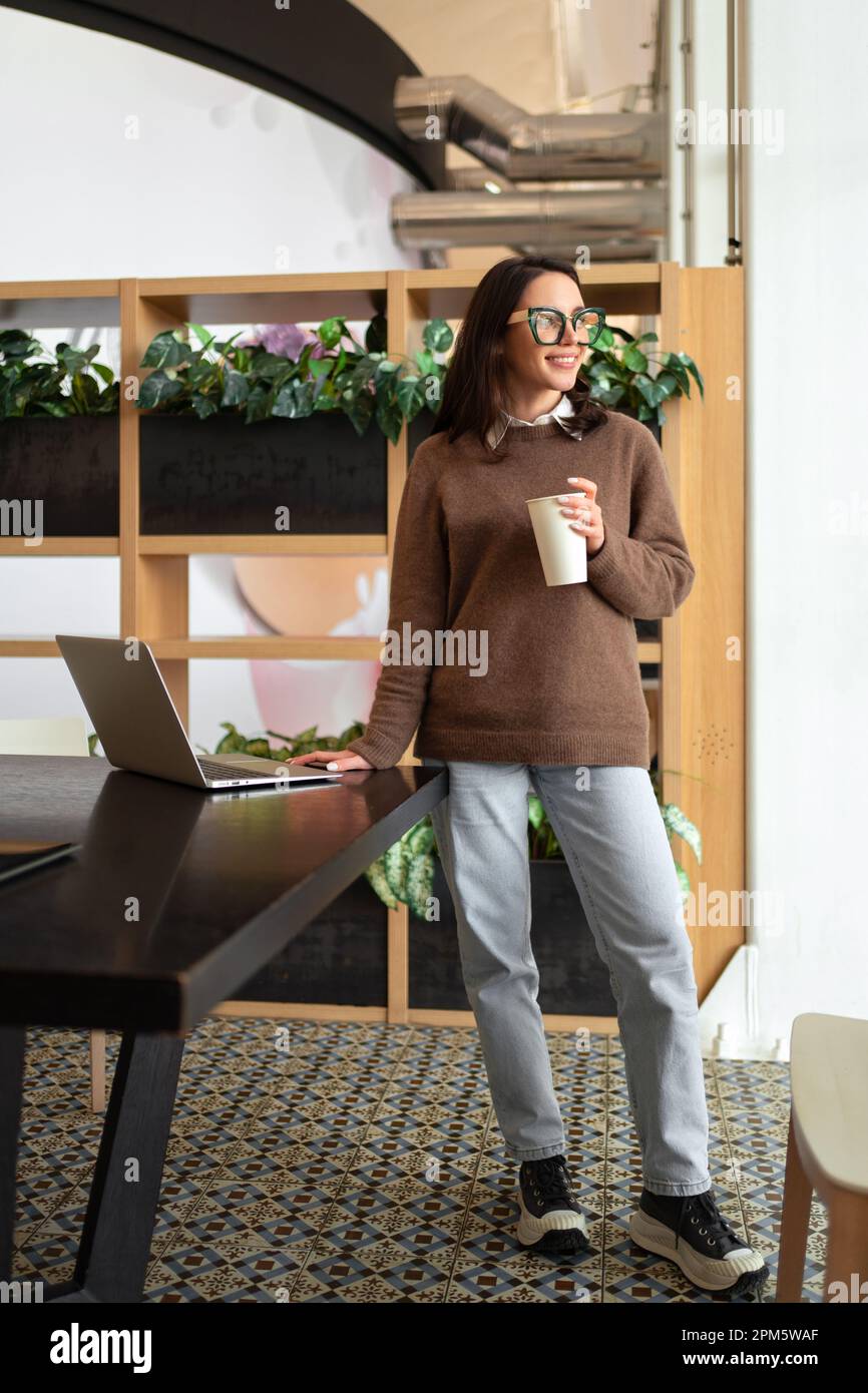 Happy European Female Entrepreneur Standing Near Desk With Laptop