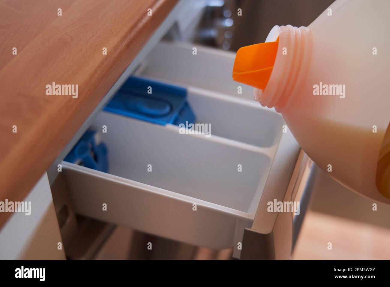 closeup pouring detergent into the compartment of a washing machine